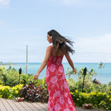 Woman wearing red sleeveless maxi dress with large pink floral print.
