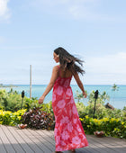 Woman wearing red sleeveless maxi dress with large pink floral print.