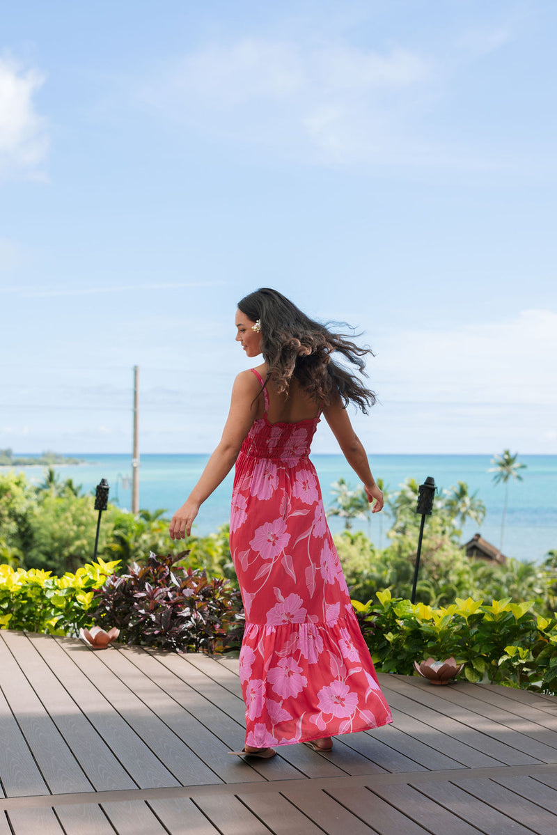 Woman wearing red sleeveless maxi dress with large pink floral print.