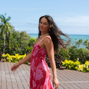 Woman wearing red sleeveless maxi dress with large pink floral print.
