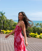 Woman wearing red sleeveless maxi dress with large pink floral print.