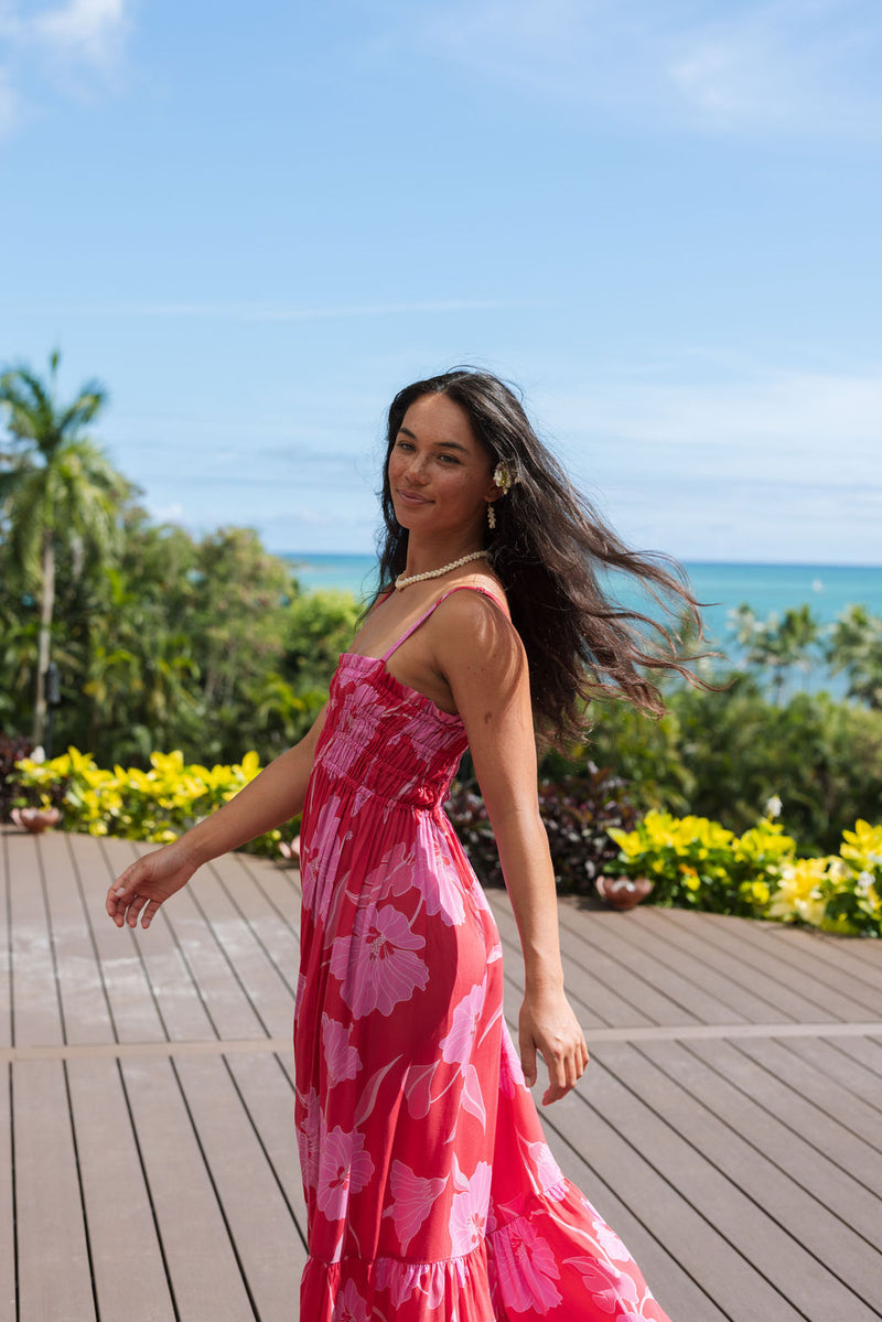 Woman wearing red sleeveless maxi dress with large pink floral print.