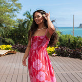 Woman wearing red sleeveless maxi dress with large pink floral print.