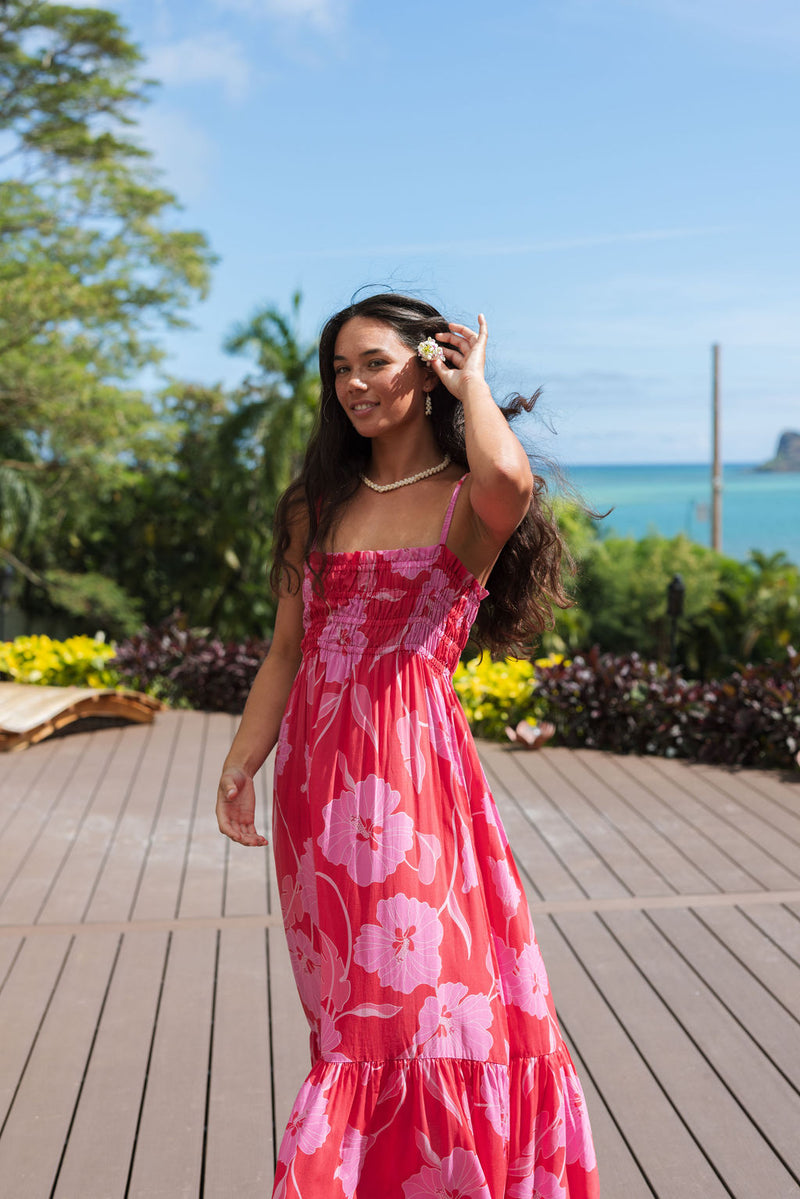 Woman wearing red sleeveless maxi dress with large pink floral print.