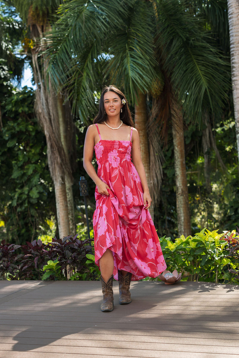 Woman wearing red sleeveless maxi dress with large pink floral print.