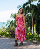 Woman wearing red sleeveless maxi dress with large pink floral print.