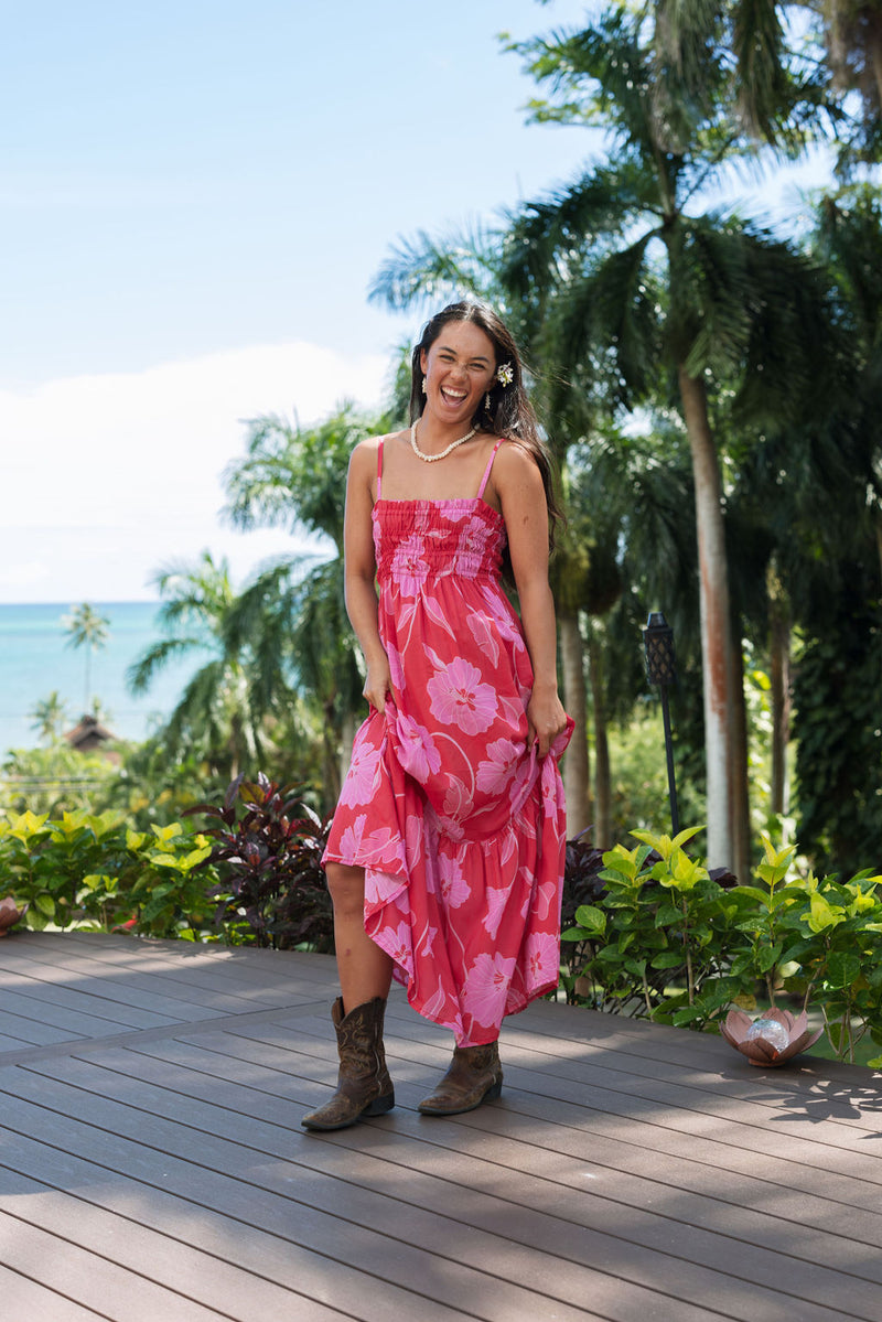 Woman wearing red sleeveless maxi dress with large pink floral print.