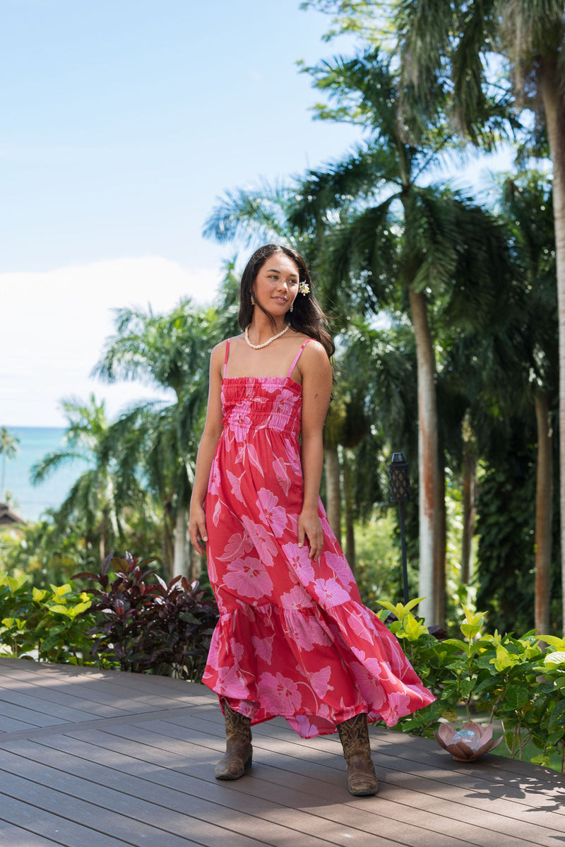 Woman wearing red sleeveless maxi dress with large pink floral print.