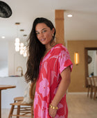 Woman wearing red short shirtdress with large pink floral print.