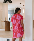 Woman wearing red short shirtdress with large pink floral print.