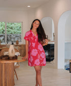 Woman wearing red short shirtdress with large pink floral print.