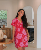 Woman wearing red short shirtdress with large pink floral print.