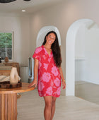 Woman wearing red short shirtdress with large pink floral print.