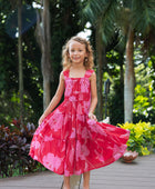 Girl wearing long red sleeveless dress with large pink floral print.