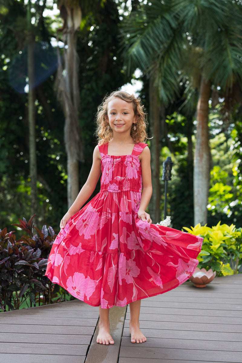 Girl wearing long red sleeveless dress with large pink floral print.