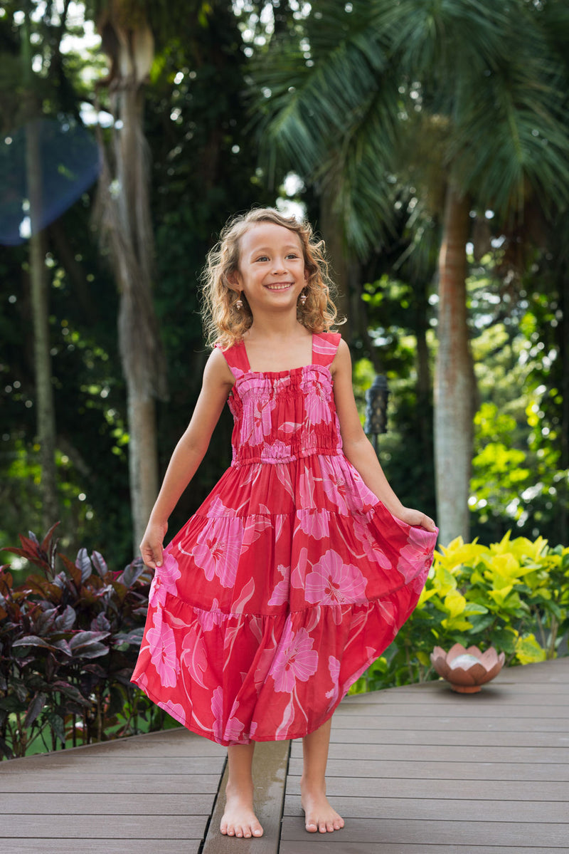 Girl wearing long red sleeveless dress with large pink floral print.