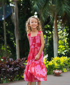 Girl wearing long red sleeveless dress with large pink floral print.