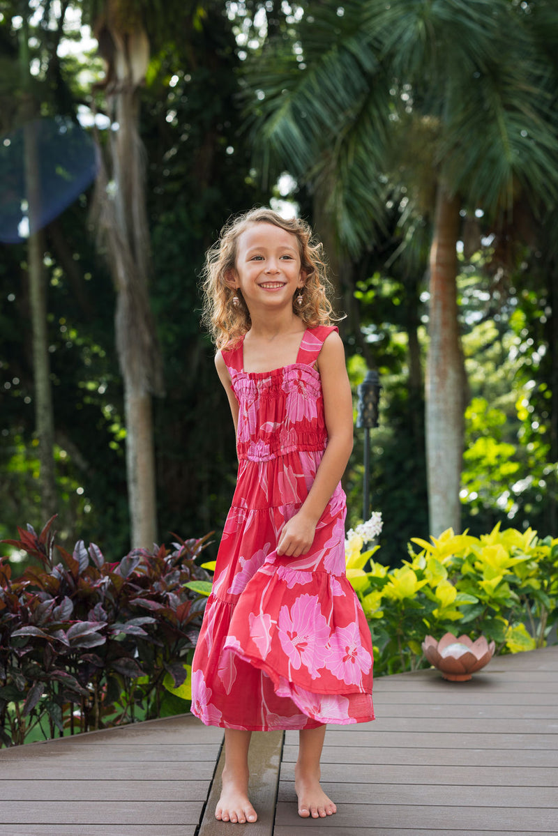 Girl wearing long red sleeveless dress with large pink floral print.