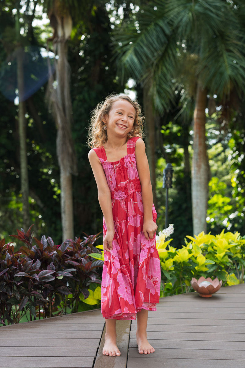 Girl wearing long red sleeveless dress with large pink floral print.