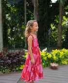 Girl wearing long red sleeveless dress with large pink floral print.