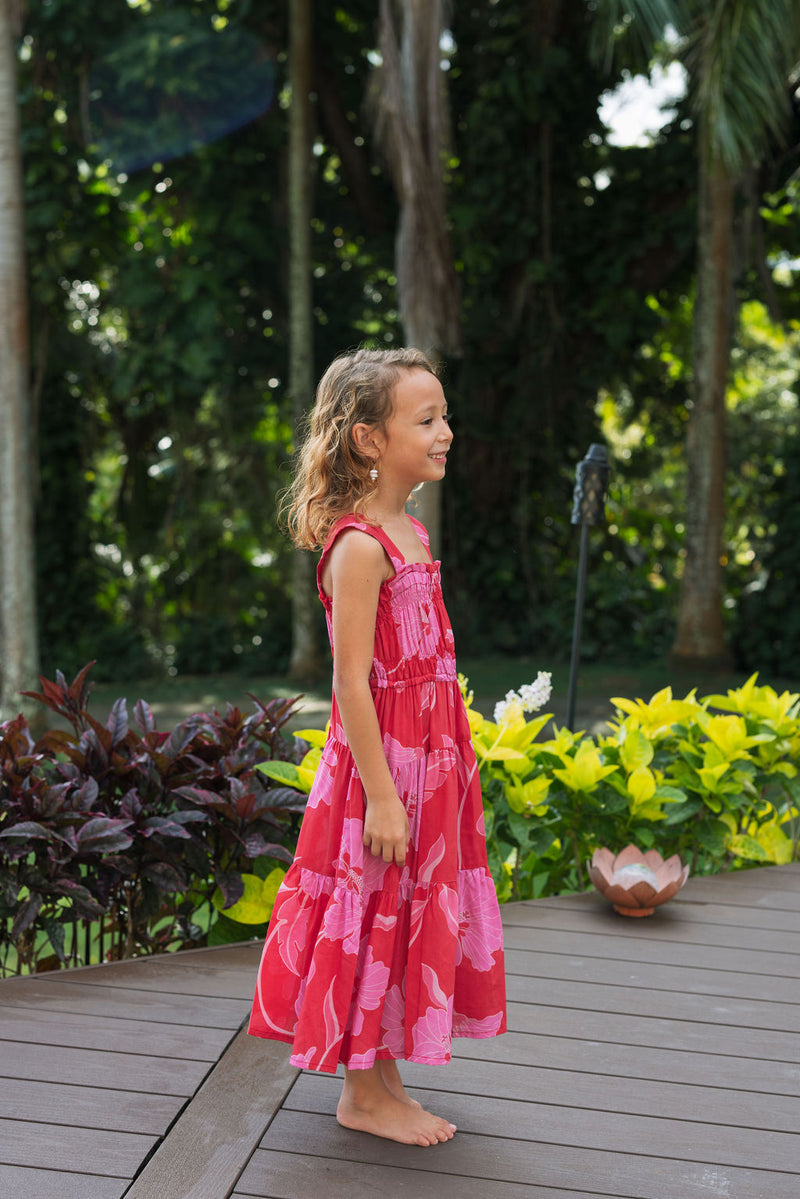 Girl wearing long red sleeveless dress with large pink floral print.