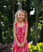 Girl wearing long red sleeveless dress with large pink floral print.