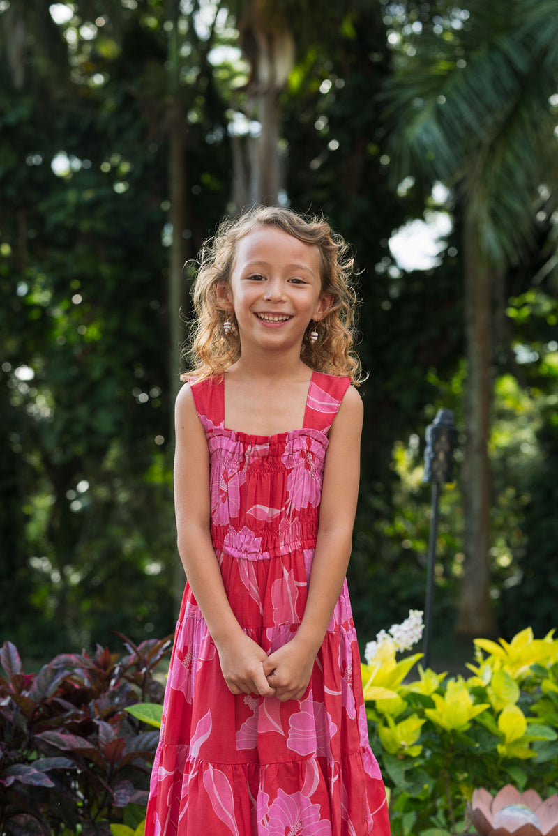 Girl wearing long red sleeveless dress with large pink floral print.