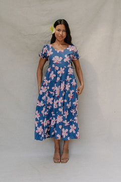 woman with brown hair wearing a navy scoop neck maxi dress with white hibiscus  print