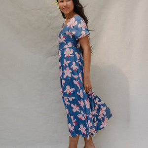 woman with brown hair wearing a navy scoop neck maxi dress with white hibiscus  print