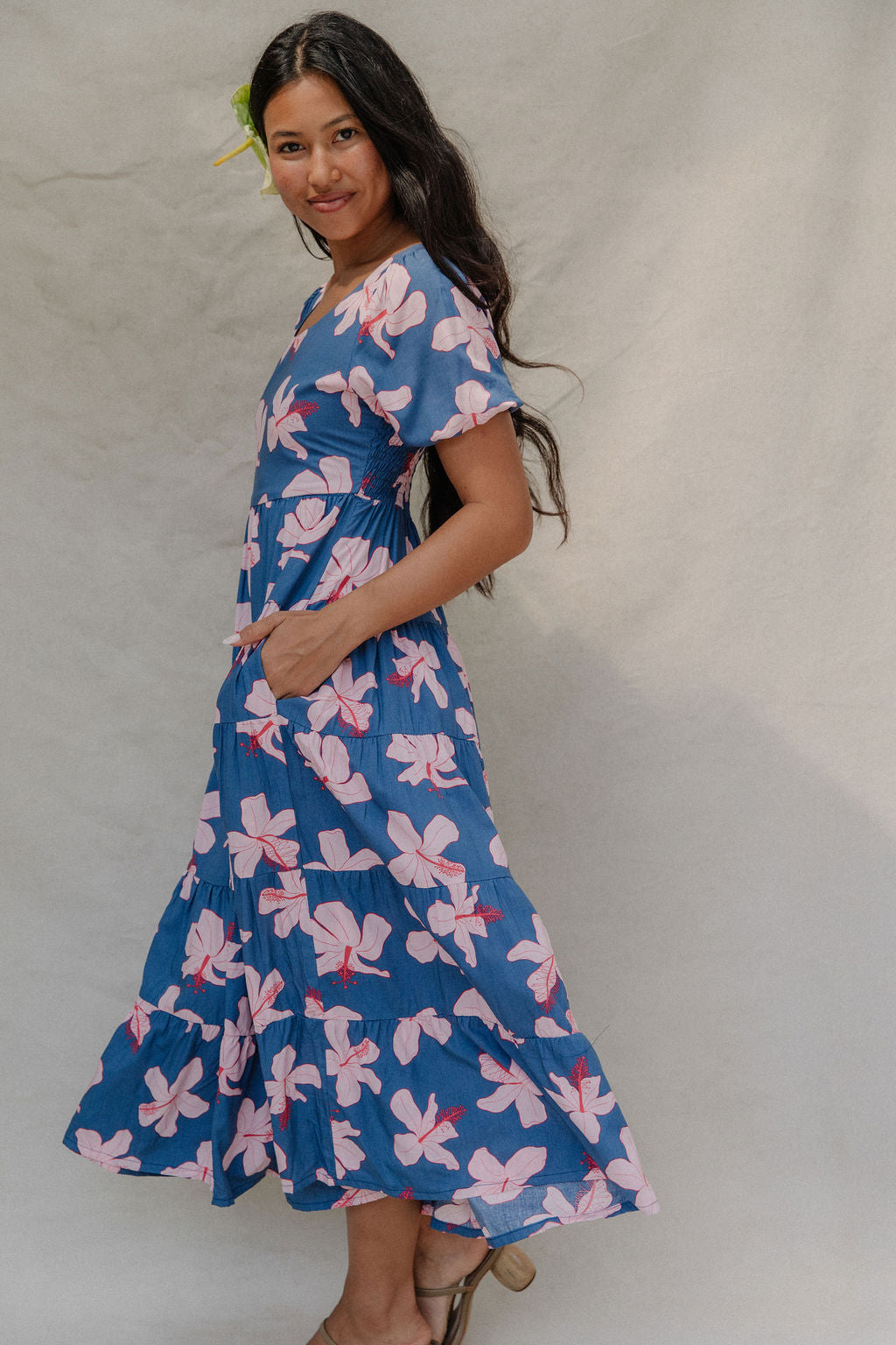 woman with brown hair wearing a navy scoop neck maxi dress with white hibiscus  print