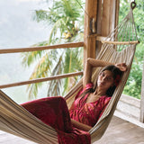 Woman with dark hair wearing tiered maxi dress with sleeves. It is the Mariana Dress in the Garden 'Awapuhi print. 