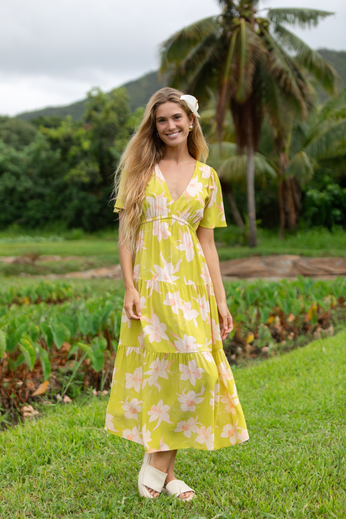 woman wearing a bright green v neck maxi dress with flutter sleeves with orchid print