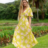 woman wearing a bright green v neck maxi dress with flutter sleeves with orchid print
