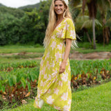 woman wearing a bright green v neck maxi dress with flutter sleeves with orchid print