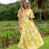 woman wearing a bright green v neck maxi dress with flutter sleeves with orchid print