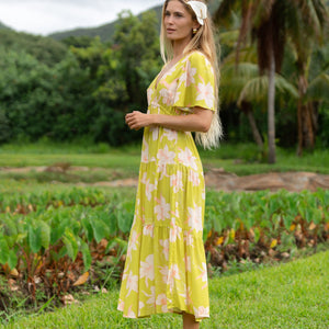 woman wearing a bright green v neck maxi dress with flutter sleeves with orchid print