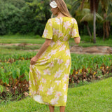 woman wearing a bright green v neck maxi dress with flutter sleeves with orchid print