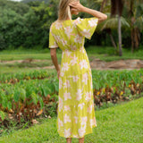 woman wearing a bright green v neck maxi dress with flutter sleeves with orchid print