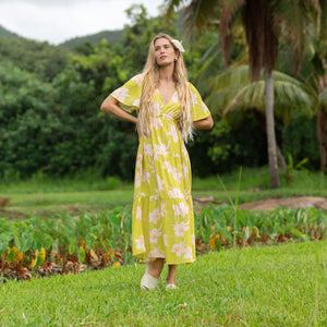 woman wearing a bright green v neck maxi dress with flutter sleeves with orchid print
