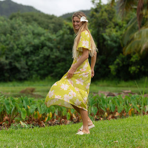 woman wearing a bright green v neck maxi dress with flutter sleeves with orchid print