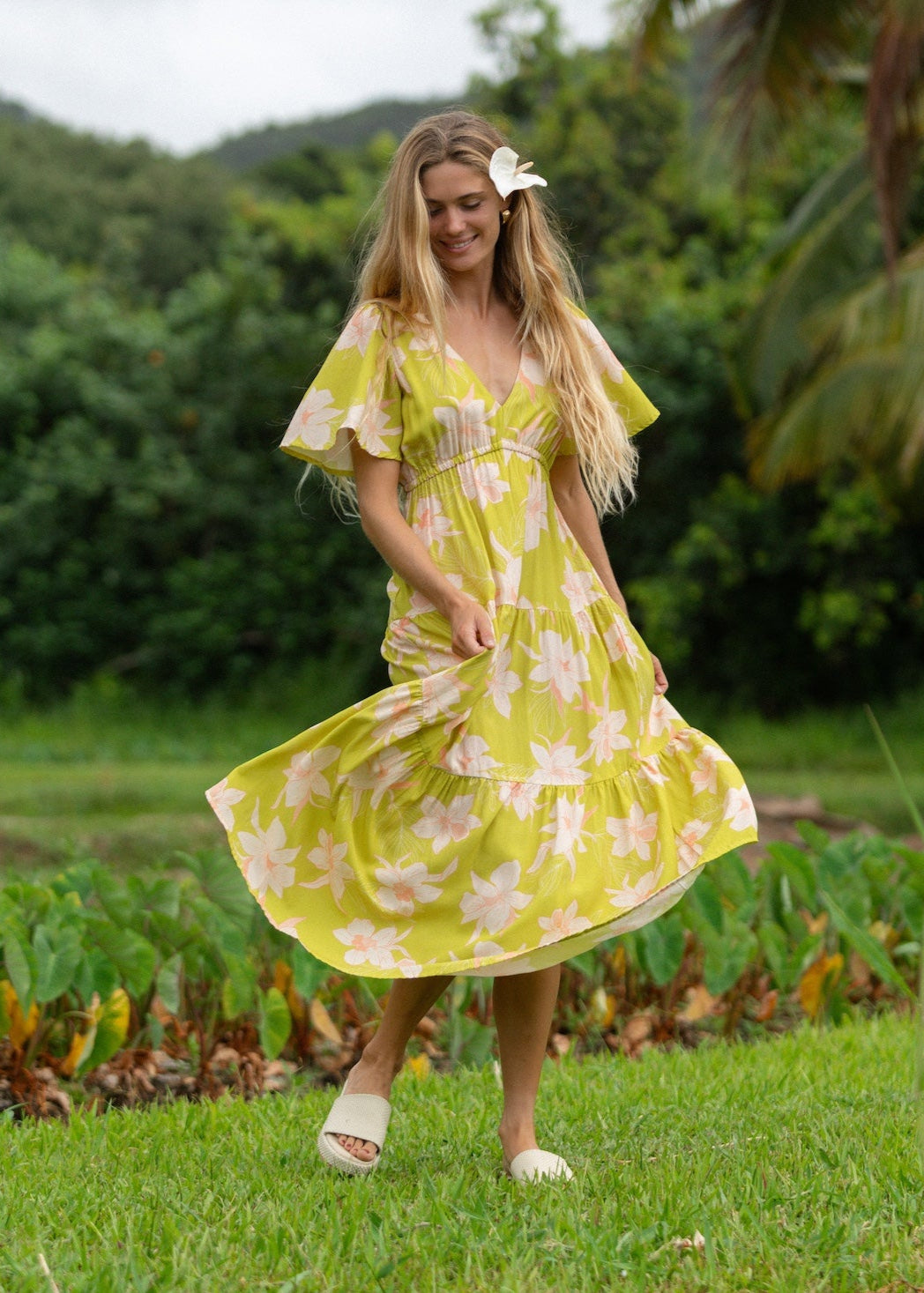 woman wearing a bright green v neck maxi dress with flutter sleeves with orchid print