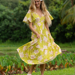 woman wearing a bright green v neck maxi dress with flutter sleeves with orchid print