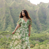 woman with brown hair wearing green v neck maxi dress with native Hawaiian plants 