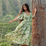 woman with brown hair wearing green v neck maxi dress with native Hawaiian plants 