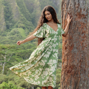 woman with brown hair wearing green v neck maxi dress with native Hawaiian plants 