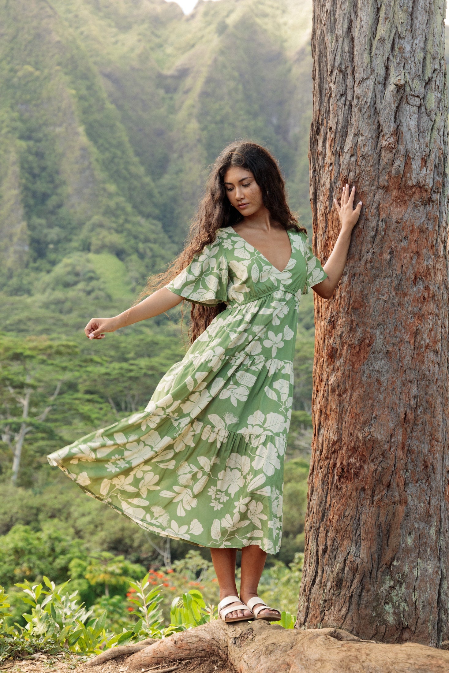woman with brown hair wearing green v neck maxi dress with native Hawaiian plants 