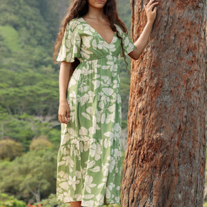 woman with brown hair wearing green v neck maxi dress with native Hawaiian plants 