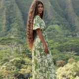 woman with brown hair wearing green v neck maxi dress with native Hawaiian plants 