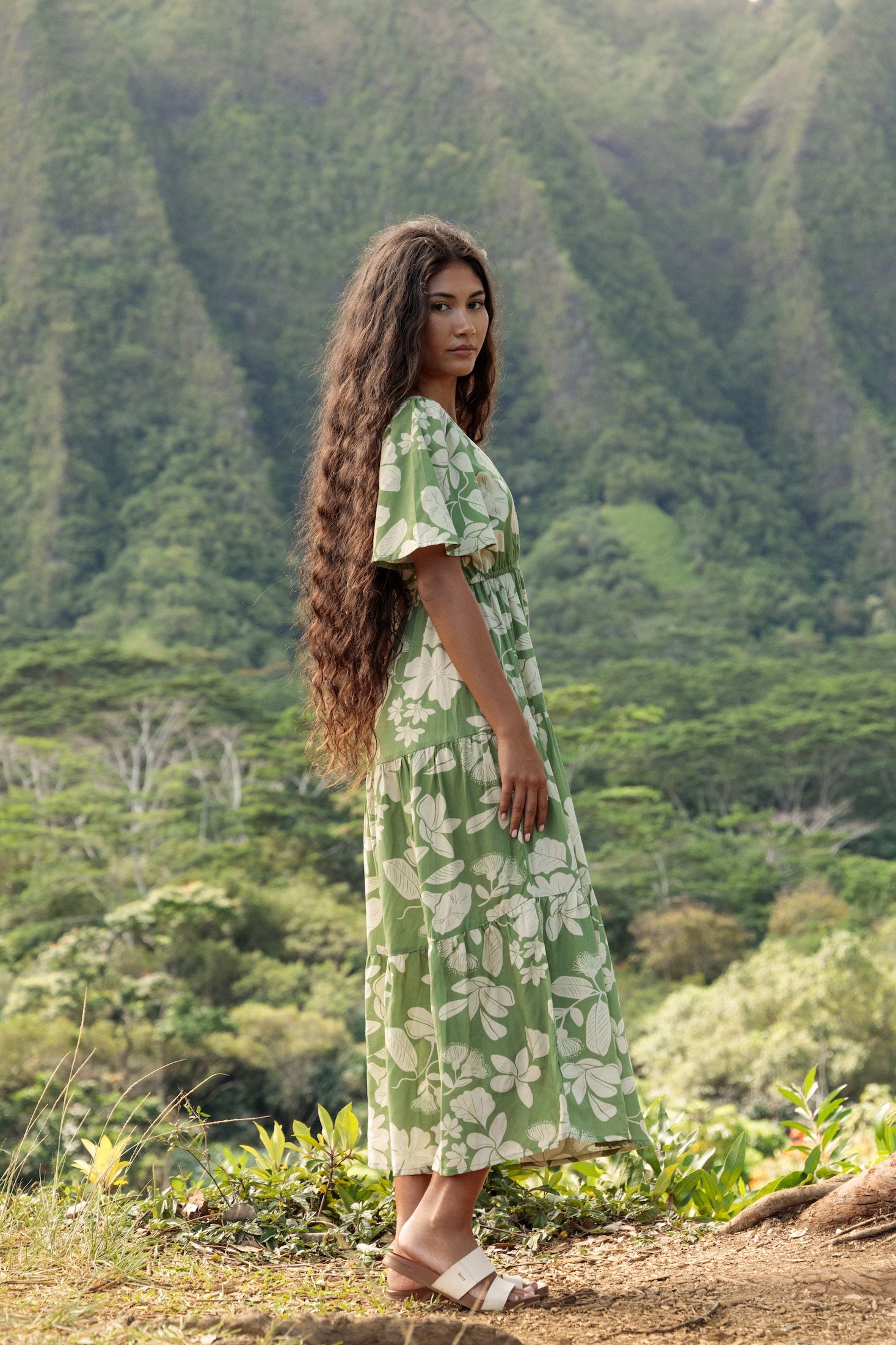 woman with brown hair wearing green v neck maxi dress with native Hawaiian plants 