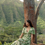 woman with brown hair wearing green v neck maxi dress with native Hawaiian plants 